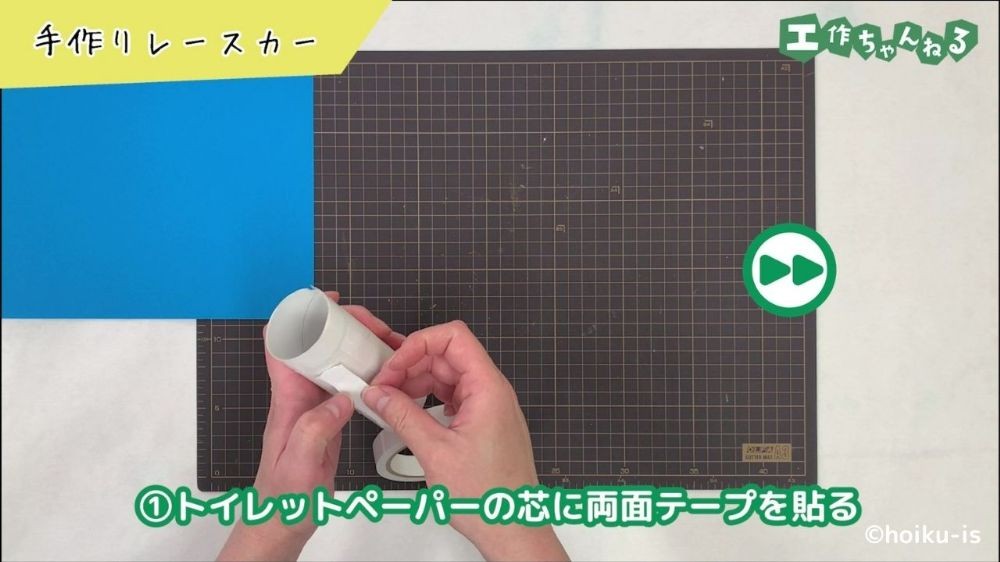トイレットペーパーの芯に両面テープを貼り付けている手元