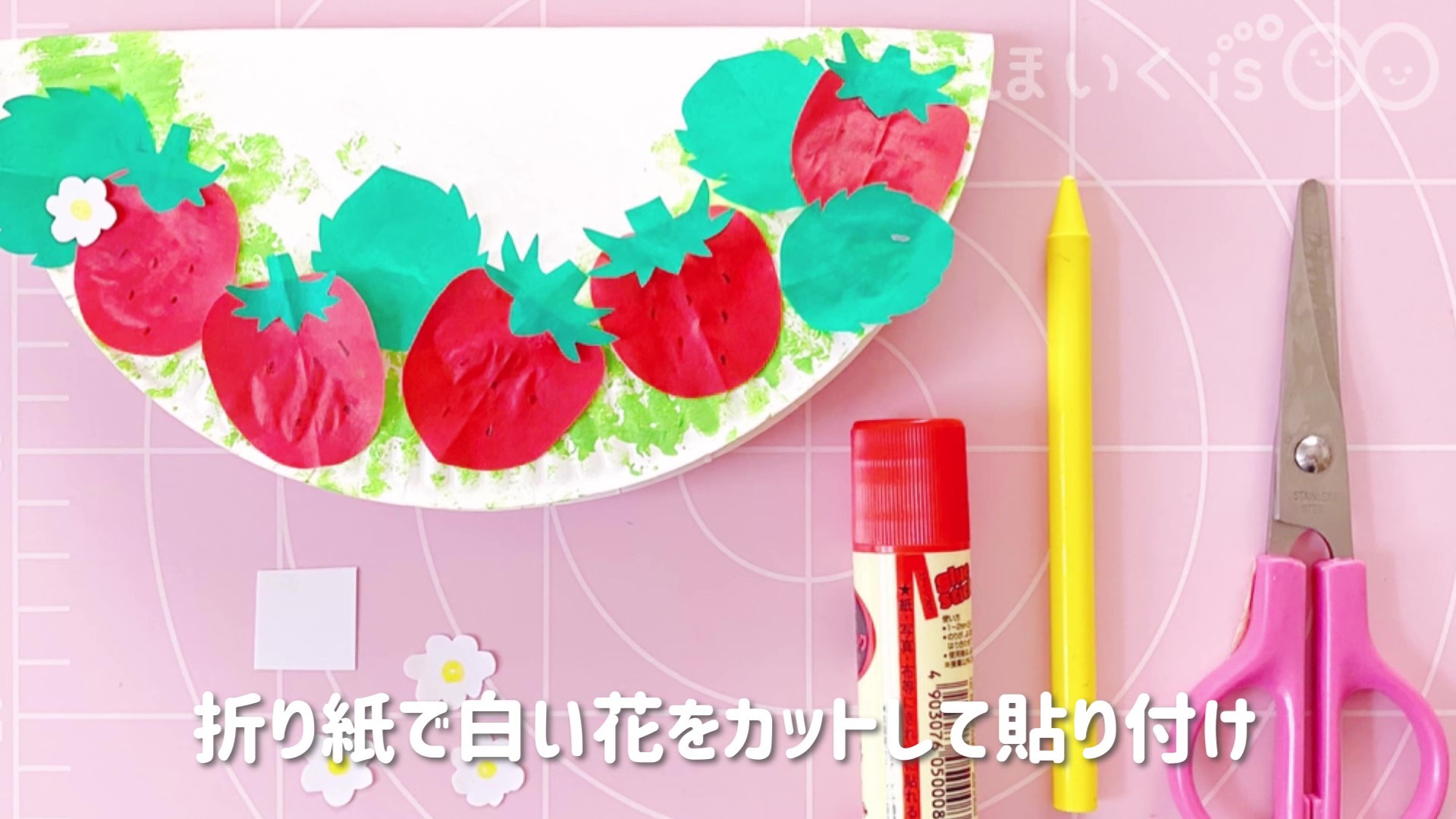 折り紙から白い花の形を切り出して紙皿に貼り付け