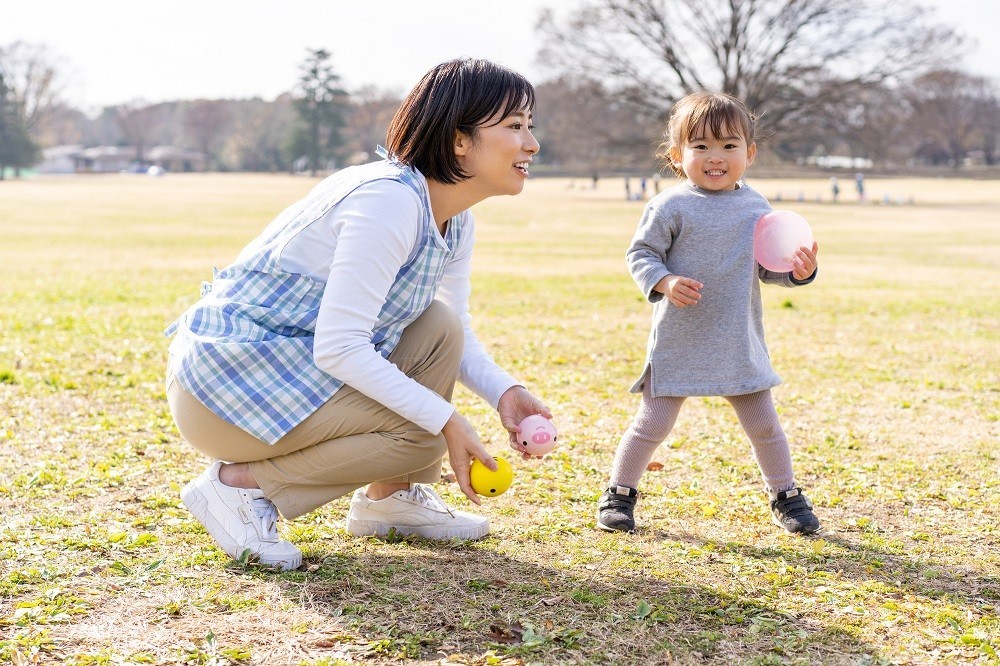 保育士とボール遊びをしている女の子