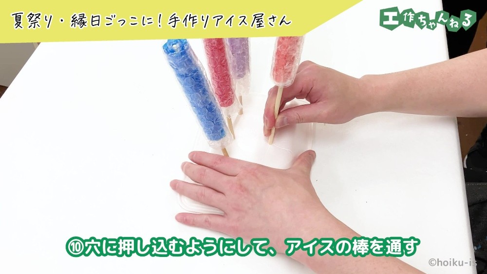 食品トレーの穴に割りばしを通している手元