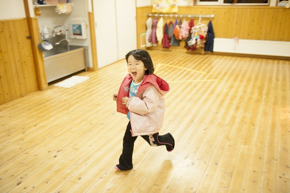 駆け足で保育室内を通り過ぎる女の子