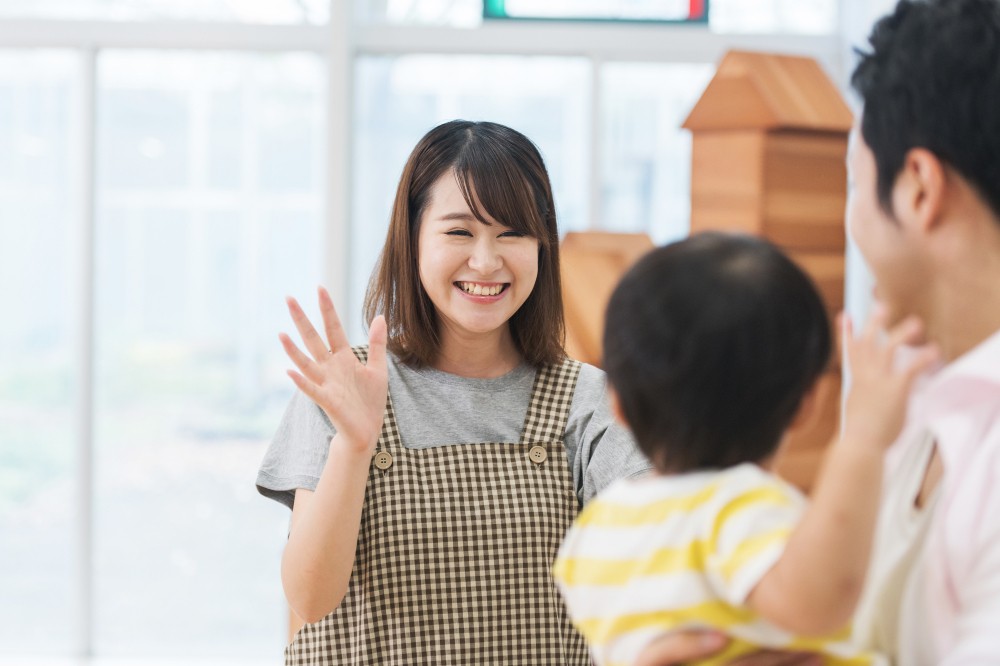 降園する園児と笑顔で見送る保育士