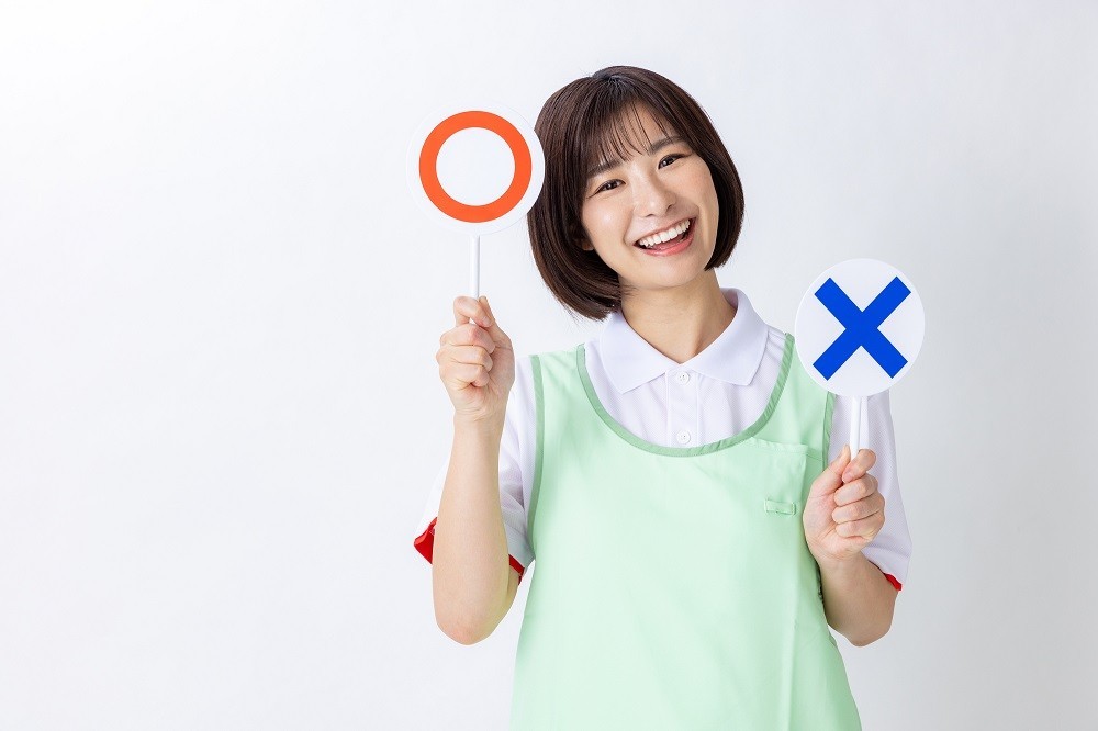 マルとバツの札を持っている保育士