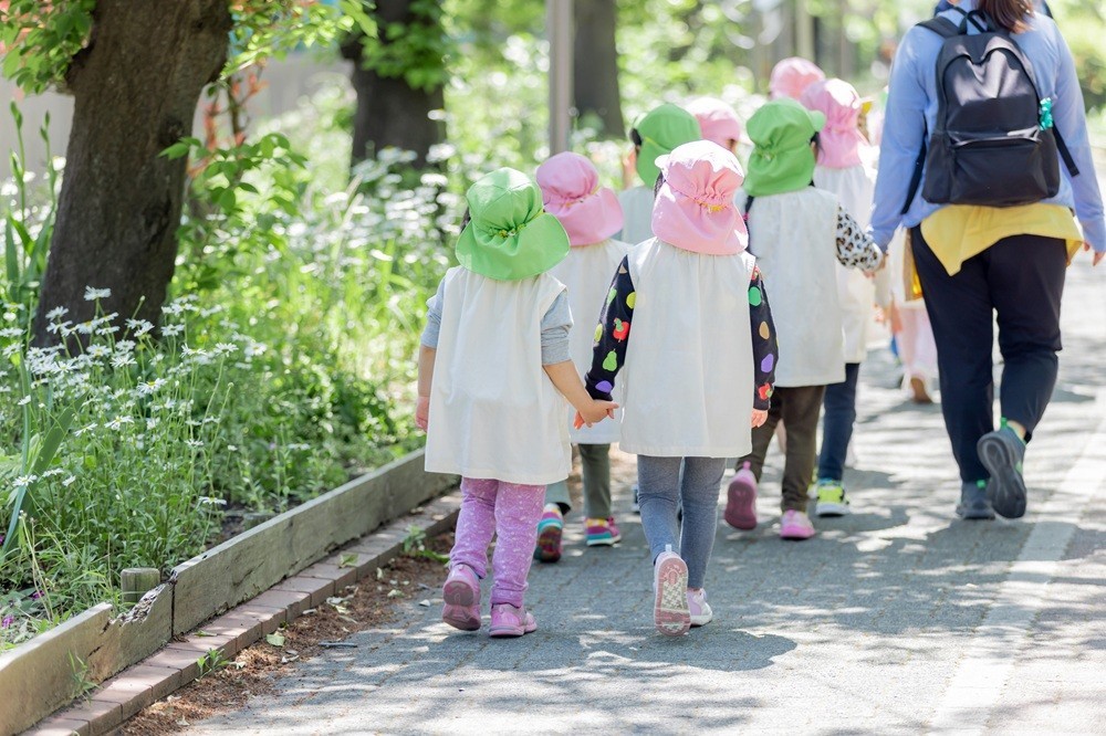 手をつないで散歩をする園児と誘導する保育士