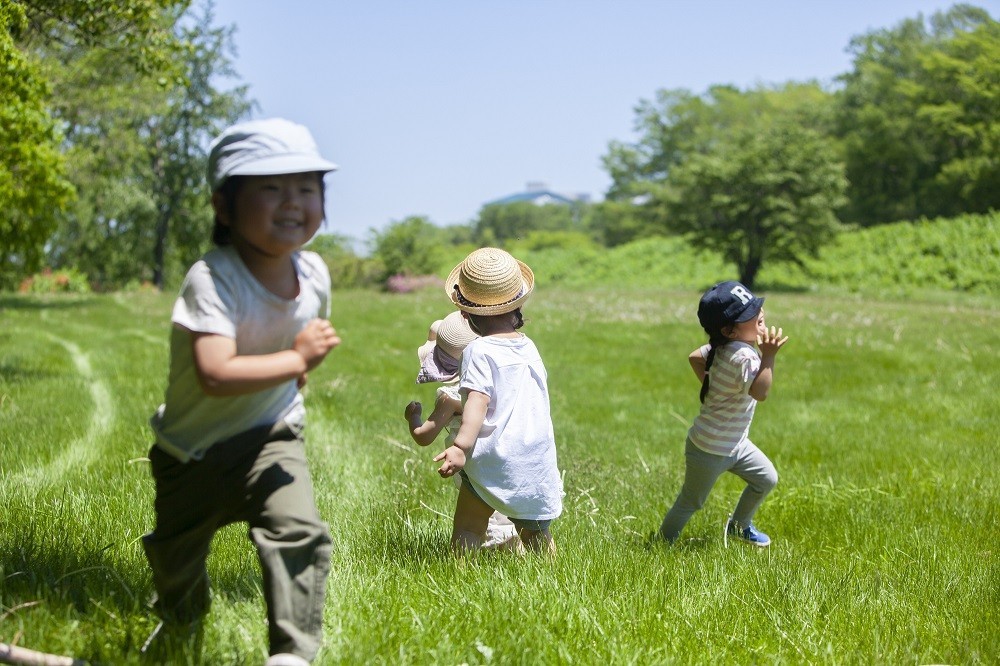 芝生の上で走っている4人の子どもたち