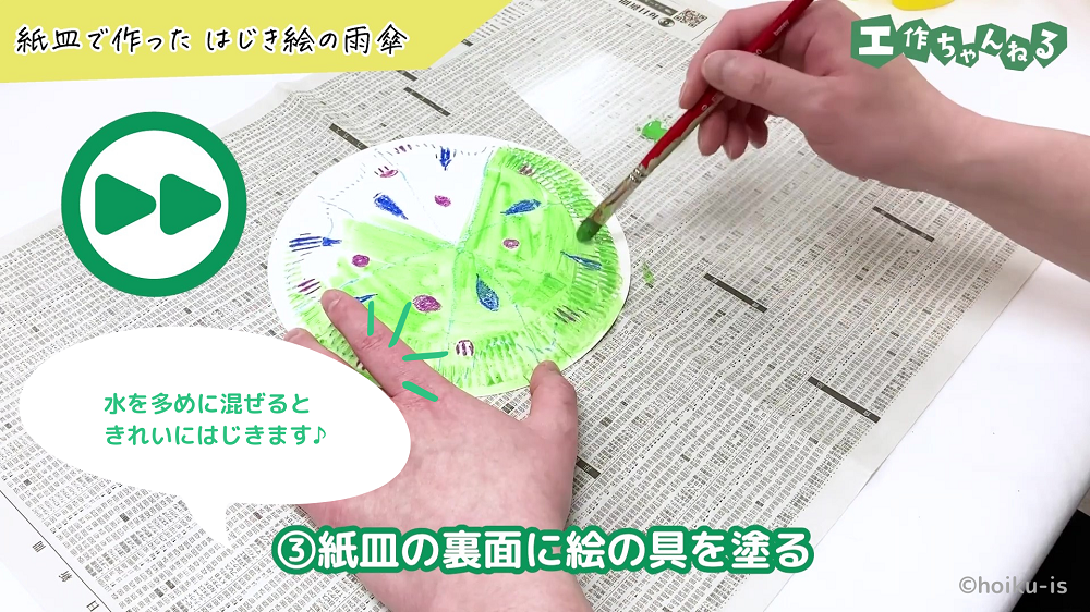 紙皿に緑色の絵の具を塗っている手元