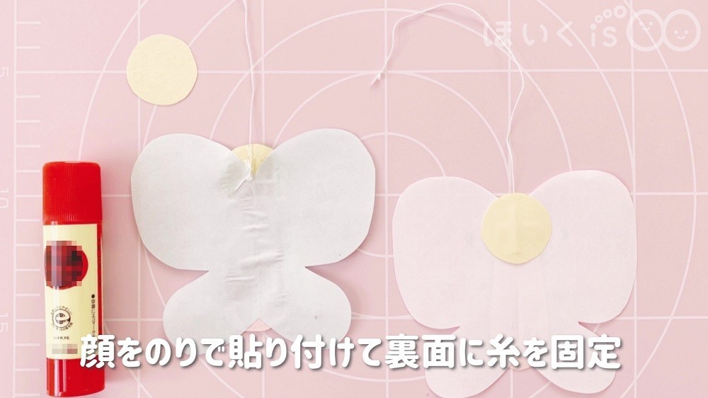 顔のパーツをスティックのりで貼り付け、裏面にはたこ糸をテープで固定します