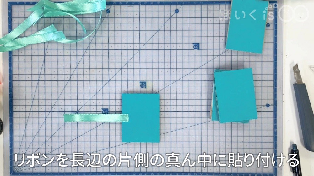 リボンを長編の片側の真ん中に張り付ける場面