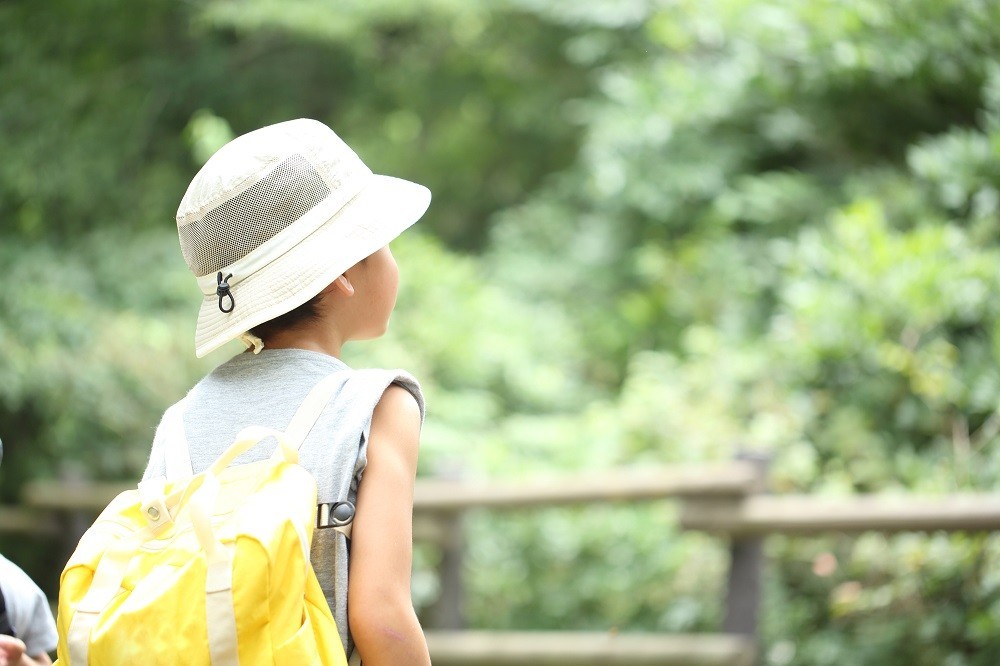 リュックサックを背負ってハイキングをする子ども
