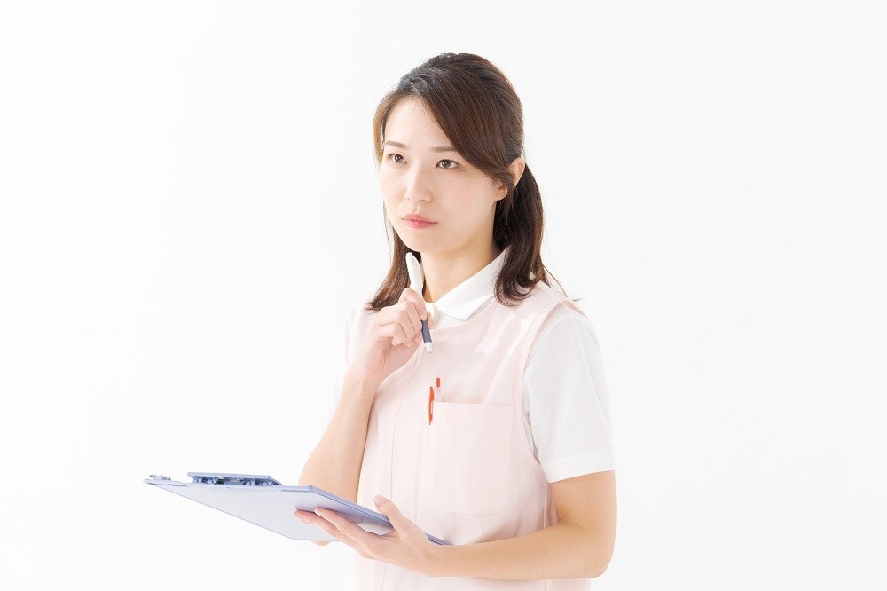 書類を持って考え事をしている保育士