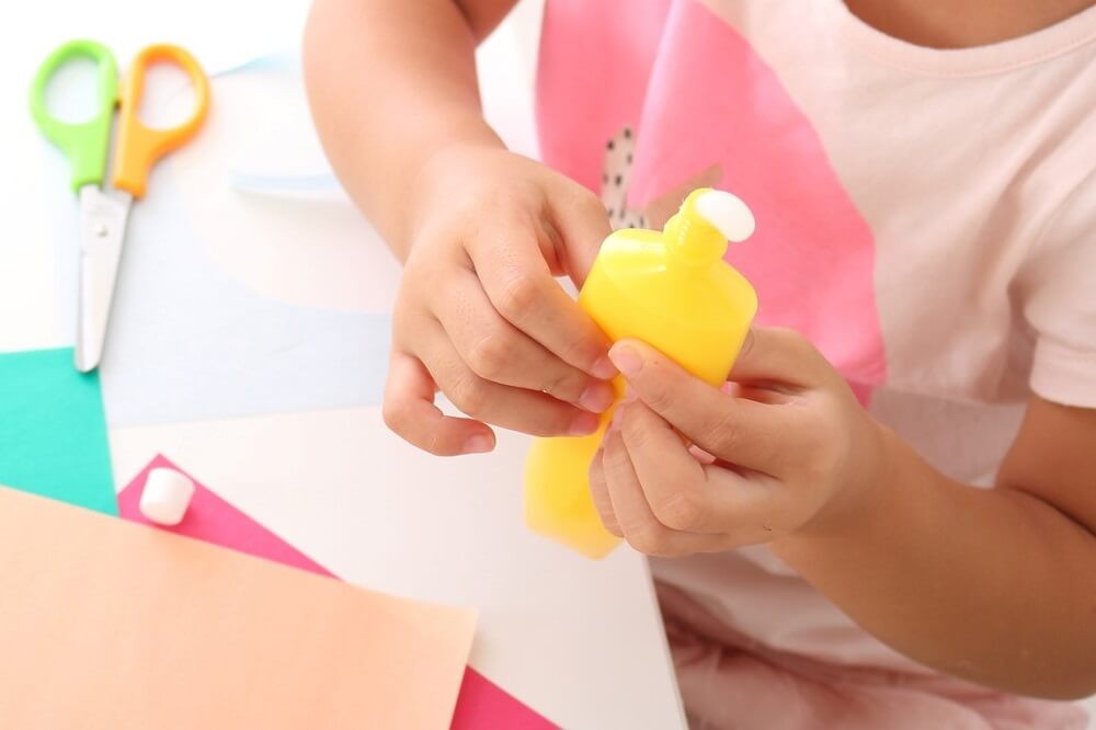 液体のりを持つ子どもの手