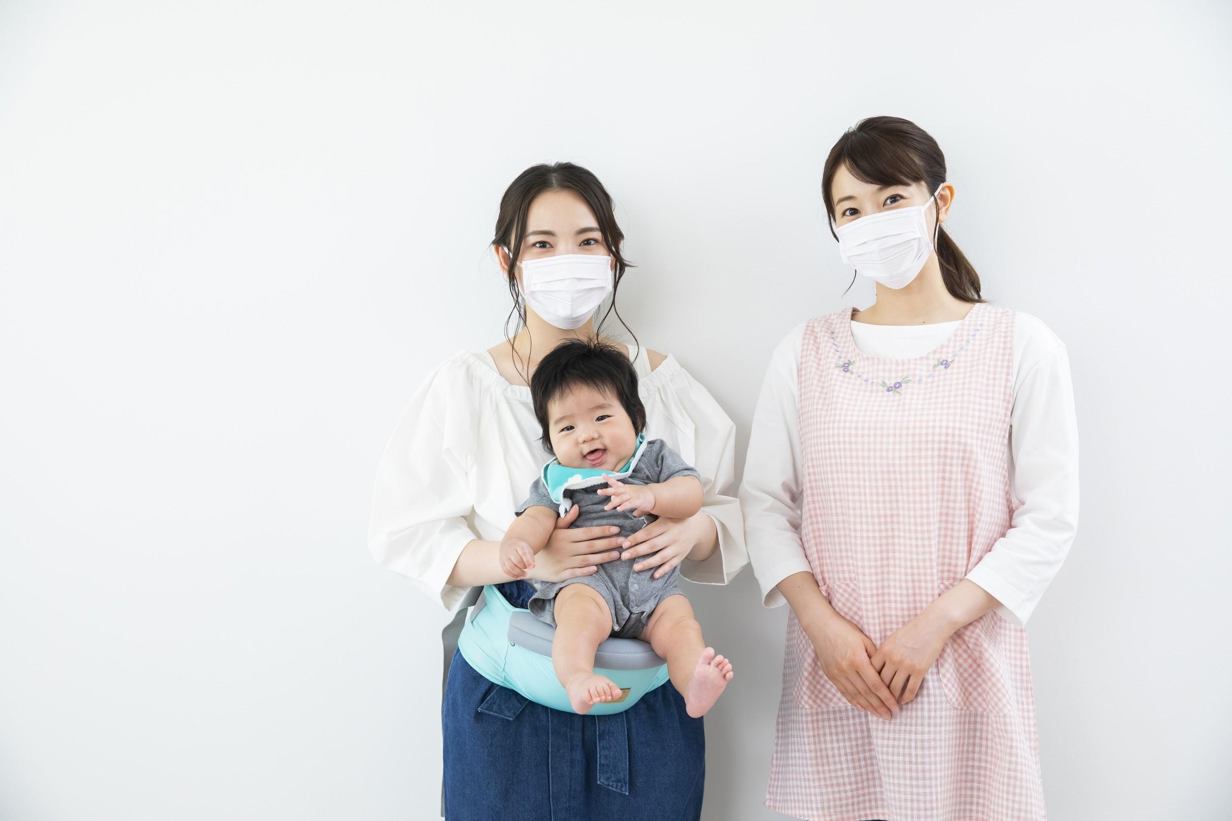 子どもを抱えた女性と保育士