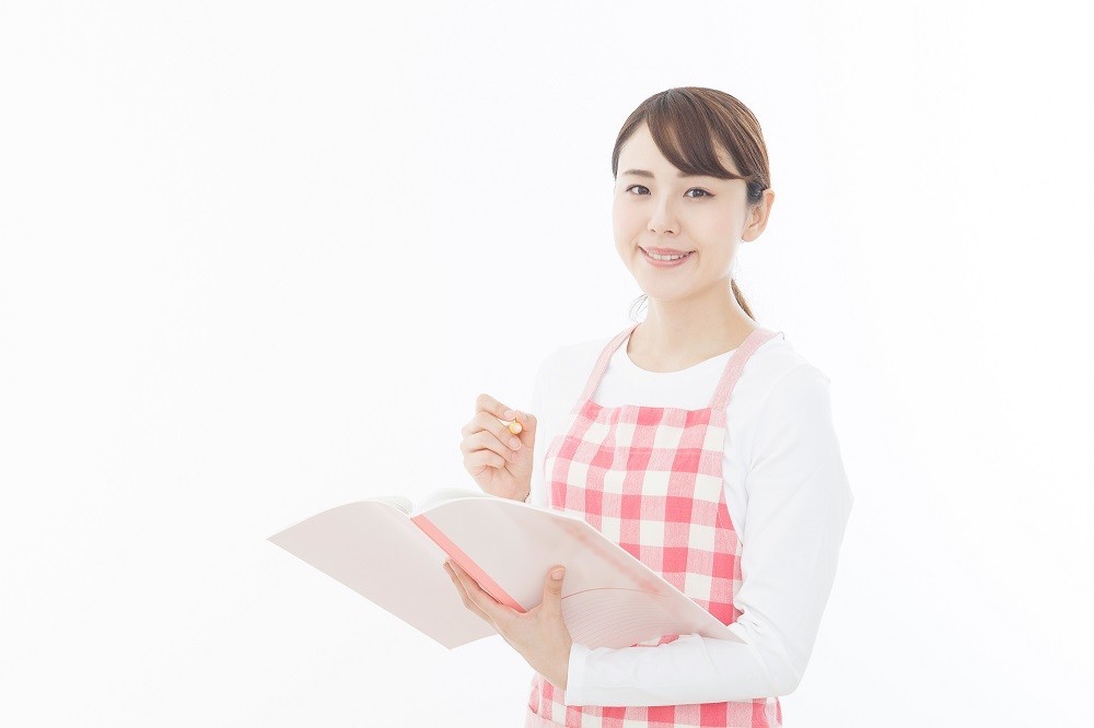 手元のノートに書き込みをする保育士