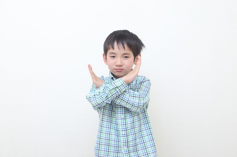 手でバツをつくる男の子