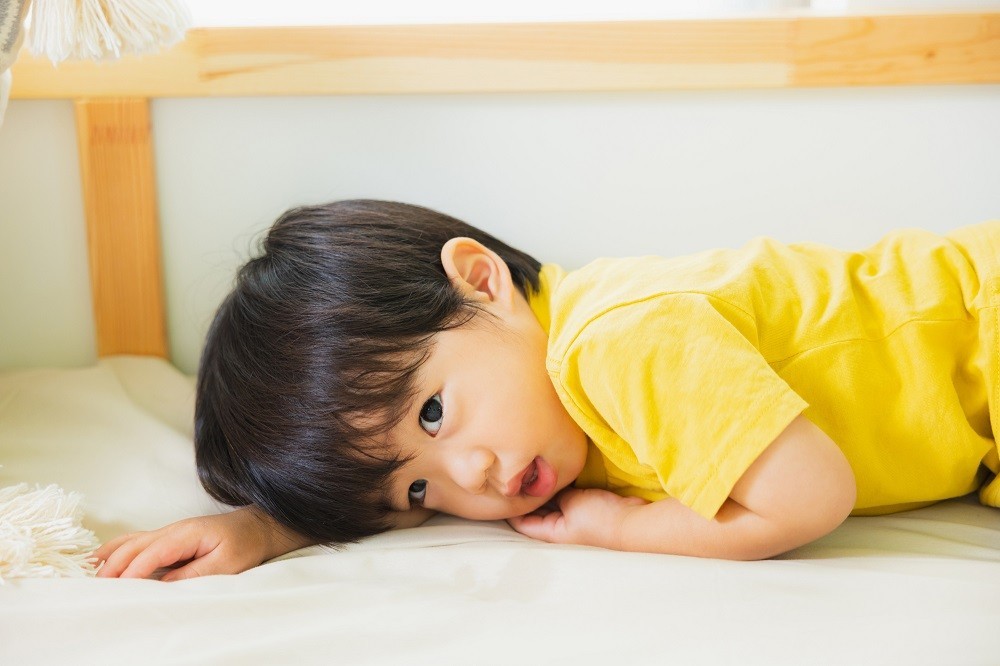 布団の上に横になっている子ども