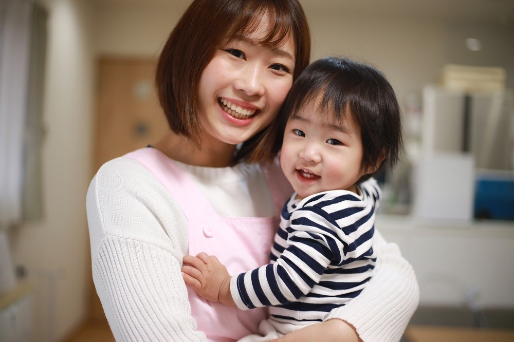 子どもを抱っこして微笑む保育士