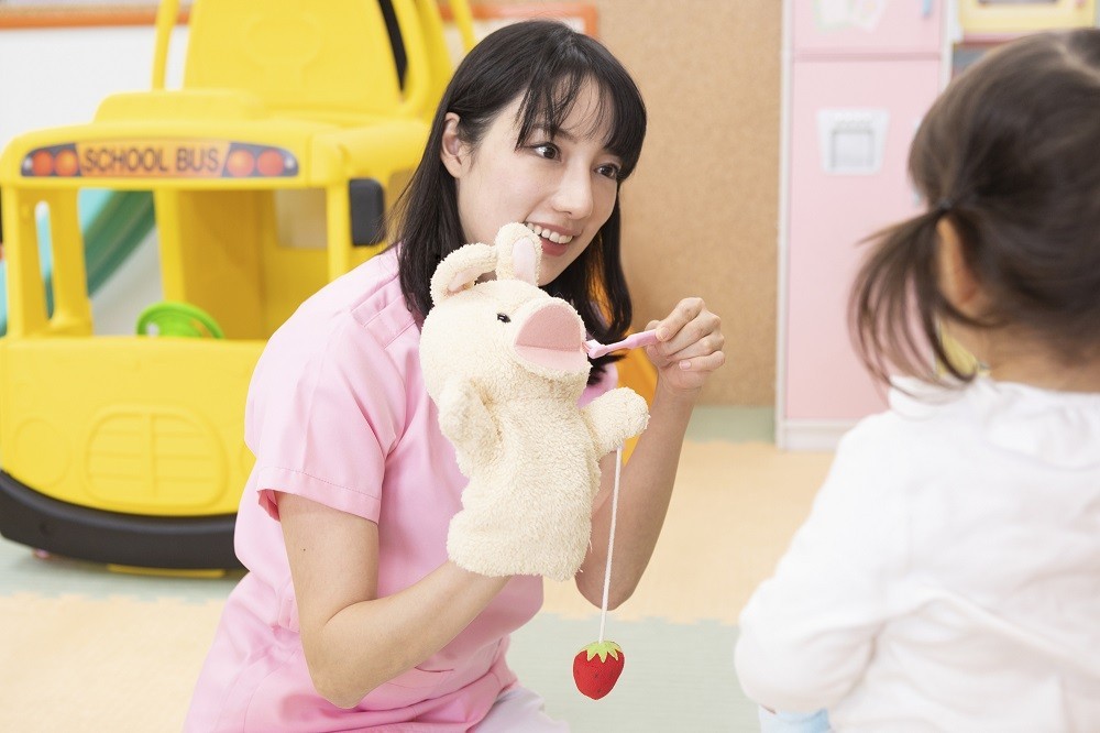 うさぎのパペットを使って歯磨きの実演をする保育士