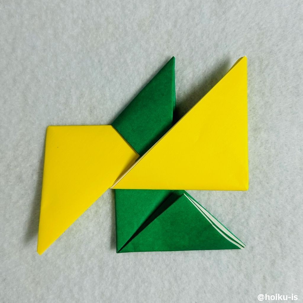 ⑬緑色の折り紙の上の三角形を中心に向かって折り、黄色の折り紙に差し込む。