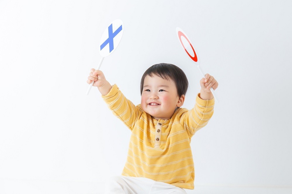 マルバツクイズのプレートを持つ子ども