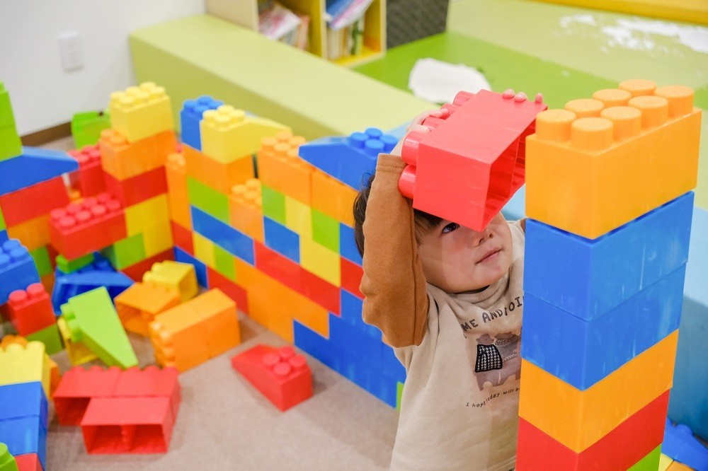 保育室内の遊具コーナーで大型ブロックを積み上げて遊ぶ男の子