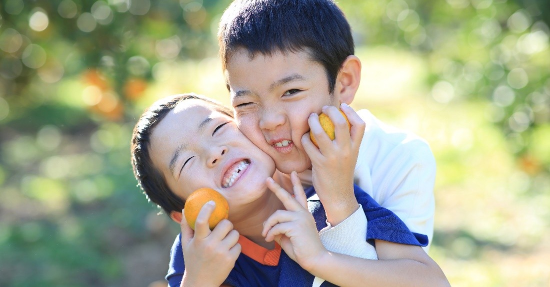 みかんをもってポーズをする子どもたち