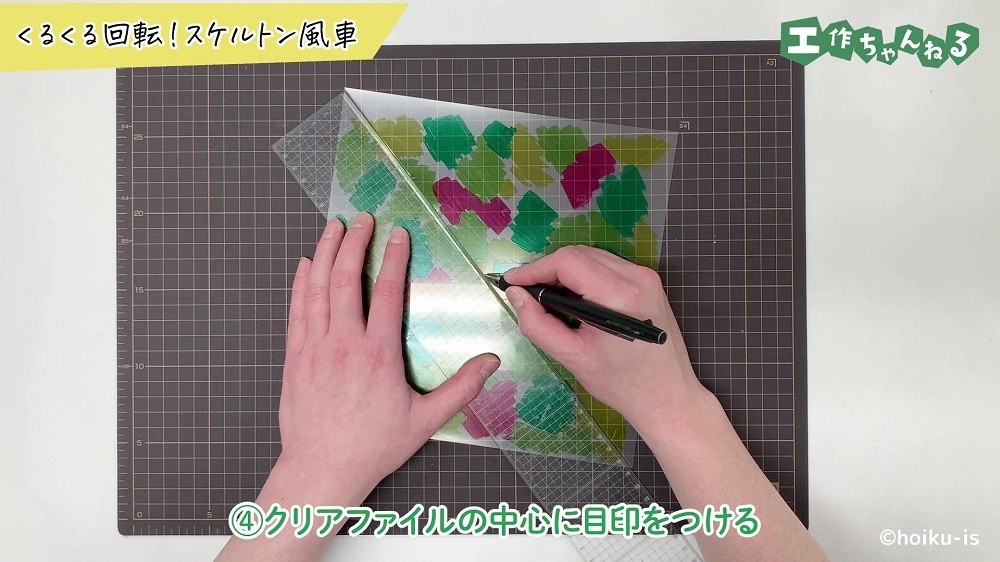 クリアファイルの中心にペンで目印を描いている手元