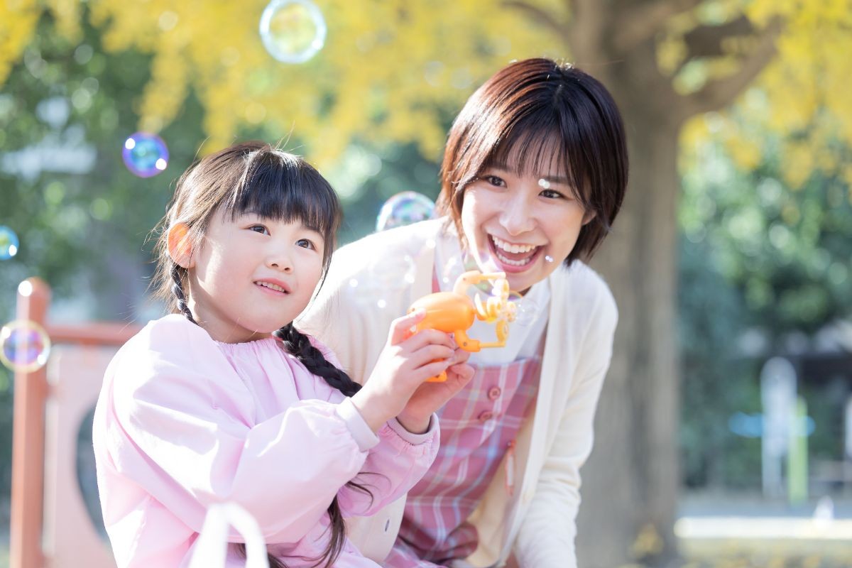 保育士とシャボン玉で遊ぶ子ども