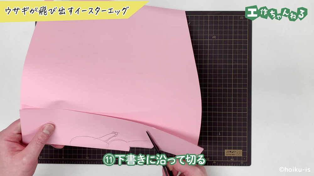 下書きに沿って画用紙を切っている手元