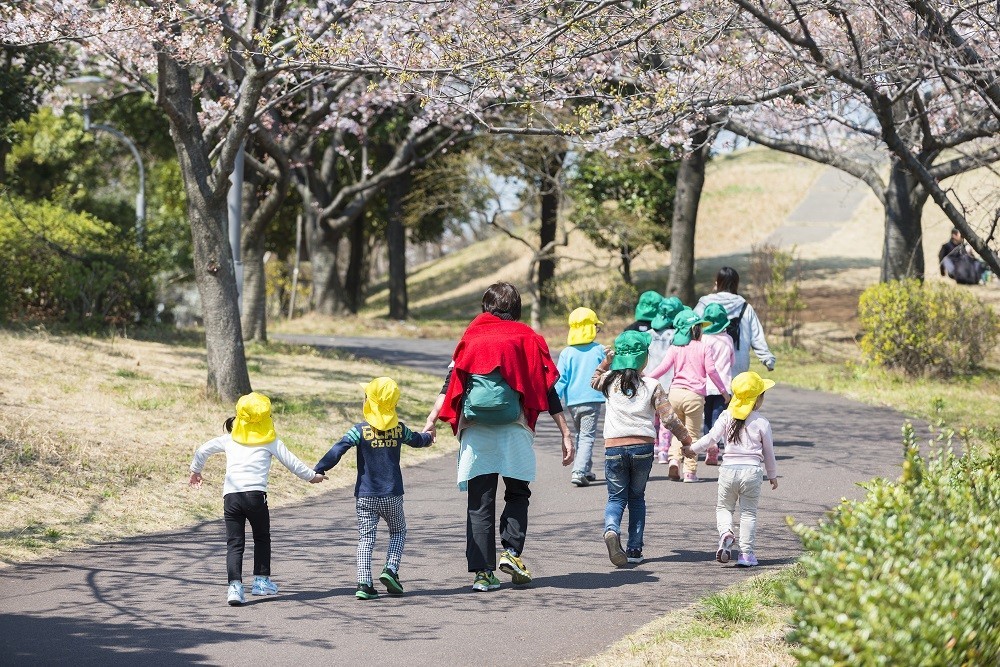 園児たちと手を繋いで散歩をする保育士