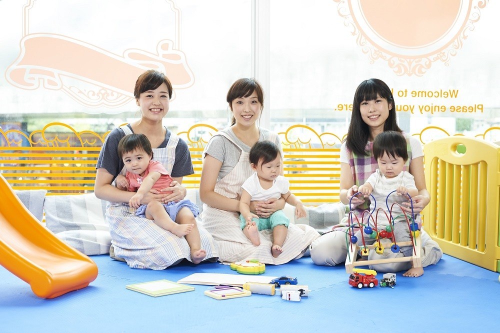 子どもを膝の上に乗せている3人の保育士
