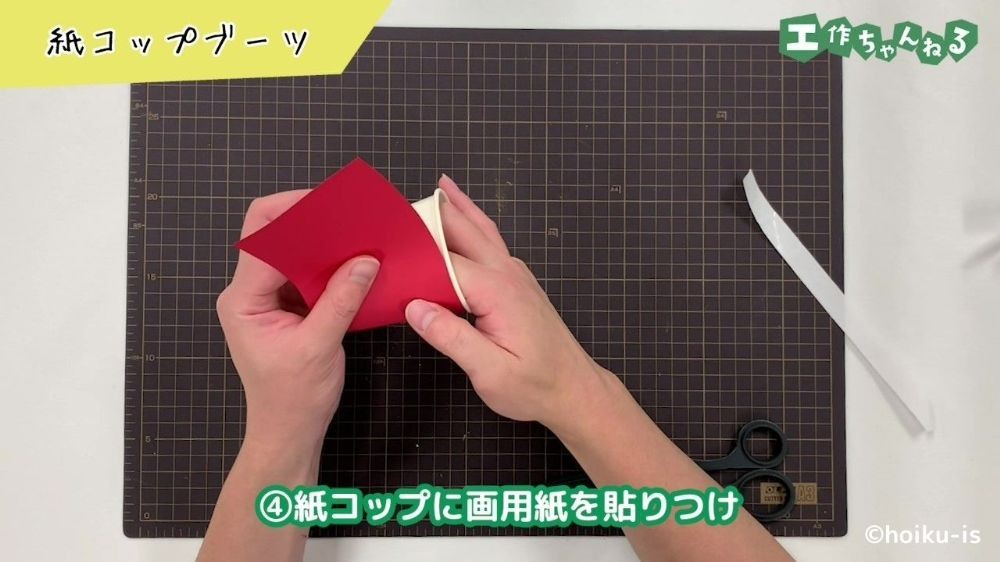紙コップに画用紙を貼り付けている手元