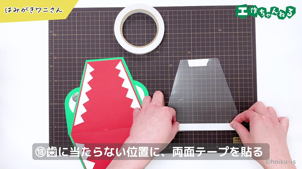 クリアファイルに両面テープを貼り付けている手元