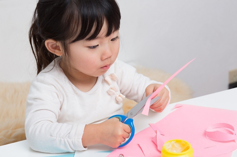 はさみで画用紙を切っている子ども