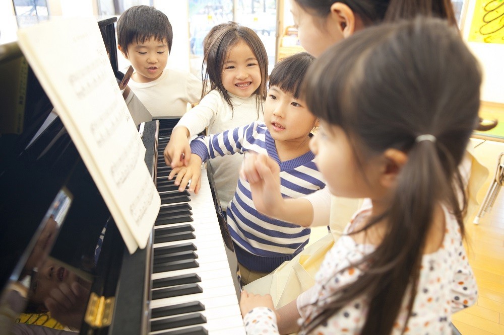 ピアノを弾く先生と子どもたち