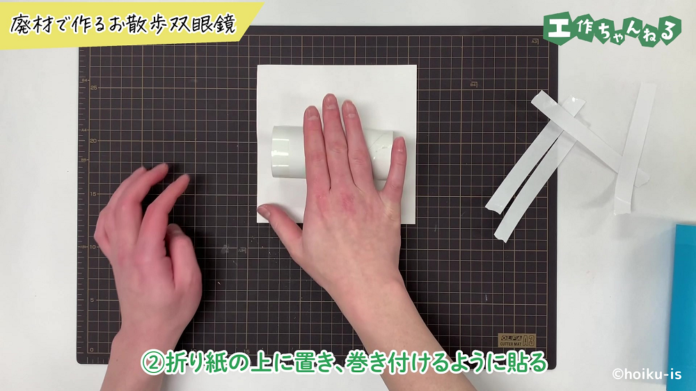 トイレットペーパーの芯に折り紙を貼り付けている手元