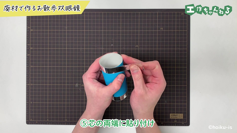 トイレットペーパーの芯に銀色の折り紙を貼り付けている手元
