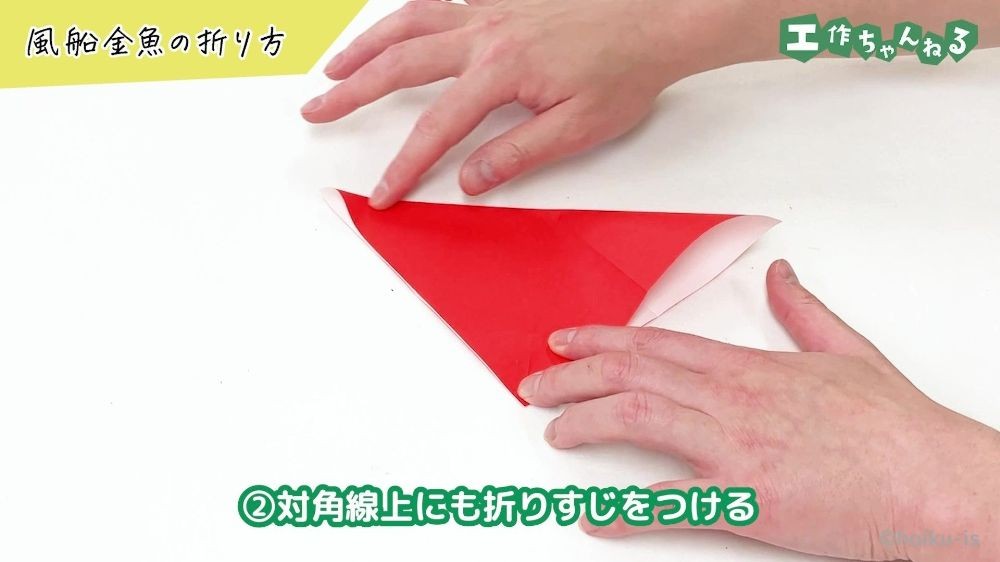 折り紙を対角線上に折っている手元