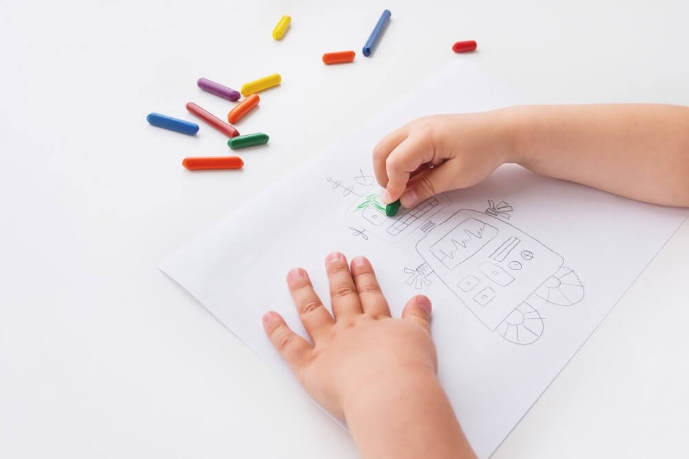 クーピーで絵を描く子どもの手