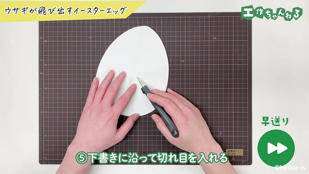 カッターで画用紙に切れ目を入れている手