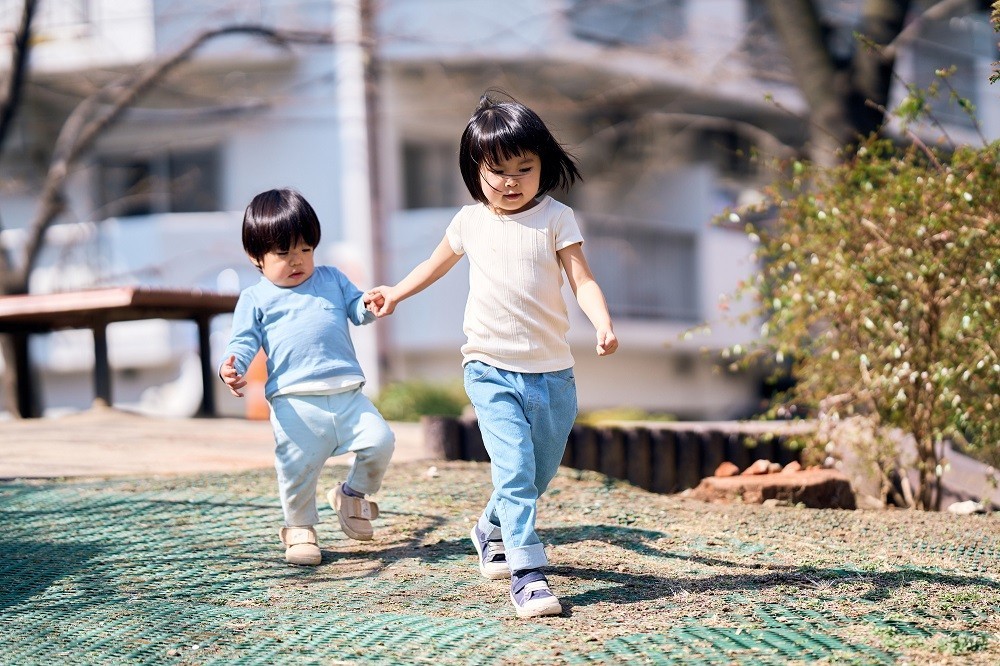 小さい子の手を引いて歩いている女の子