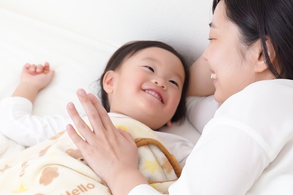 子どもと添い寝をしている保育士