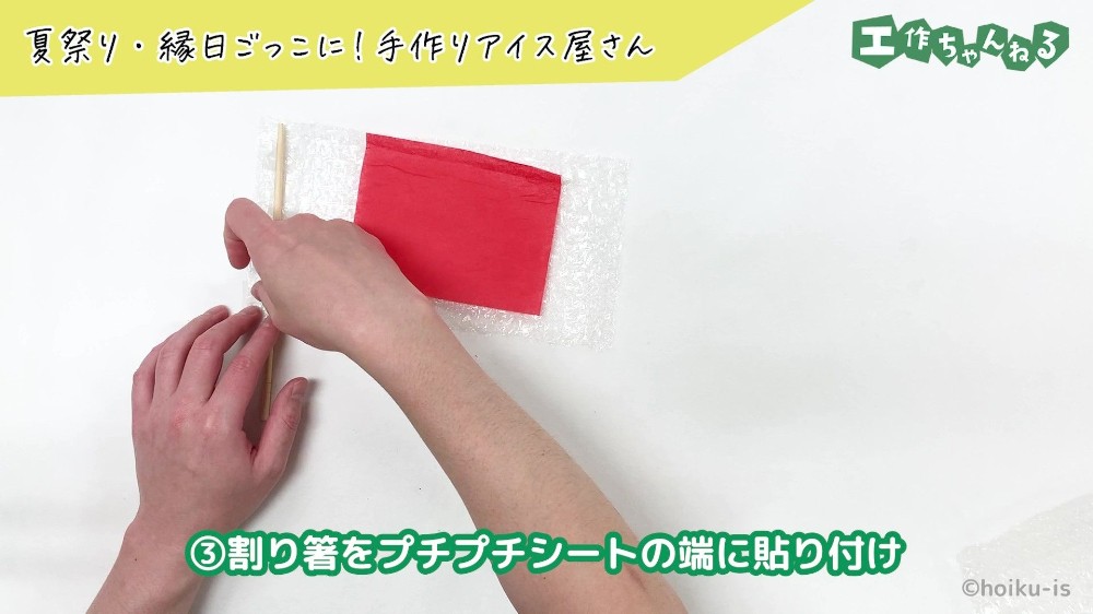 セロハンテープで割りばしを貼り付けている手元