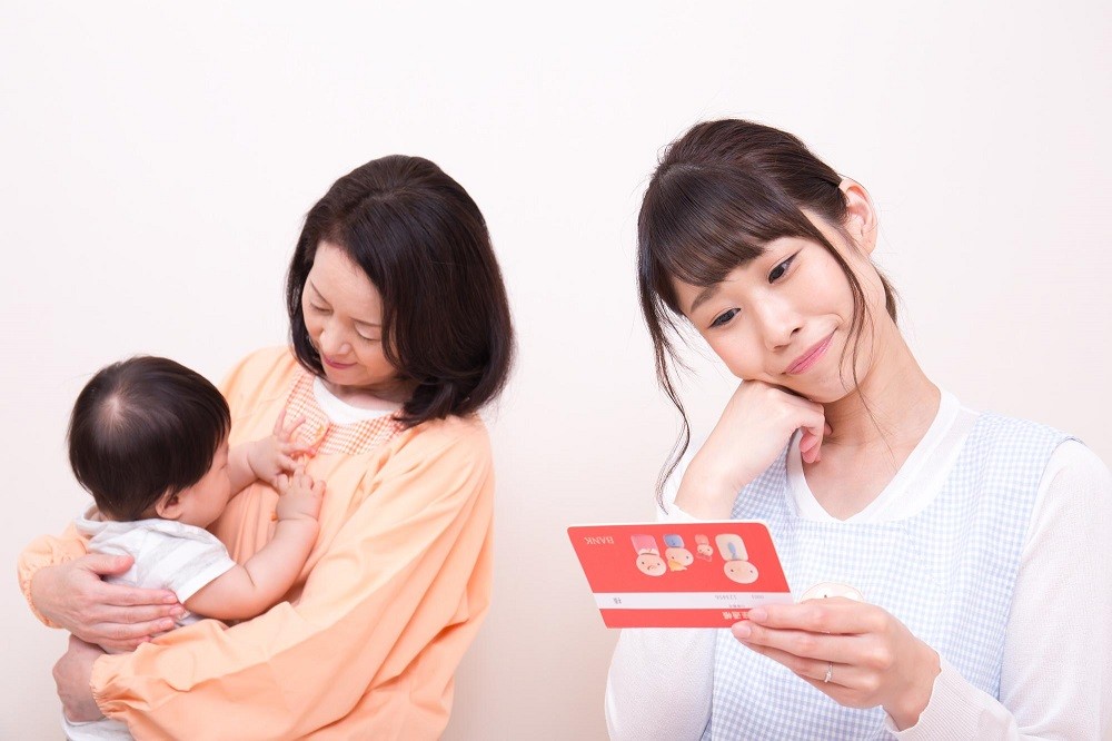 ベテラン保育士、子どもと給与明細を見る保育士