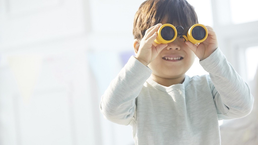 手に持った双眼鏡を覗いている男の子