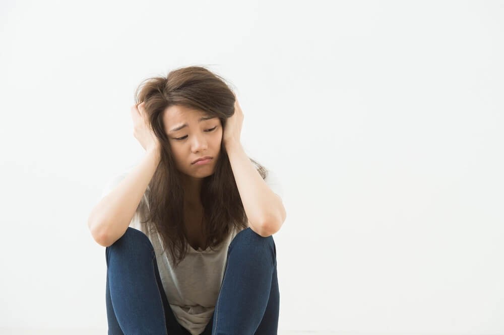 頭を抱えて悩んでいる女性