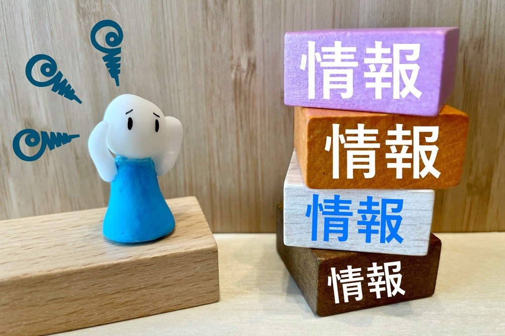 たくさん積まれた「情報」と書かれた積み木と人形