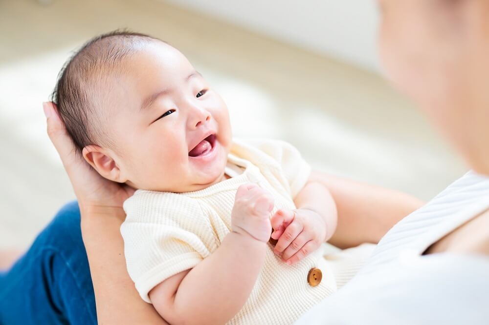 保育士に抱っこされる赤ちゃんの画像