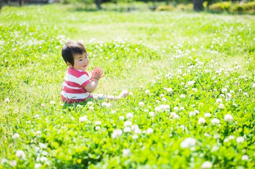 草が生い茂る地面に座っている子ども
