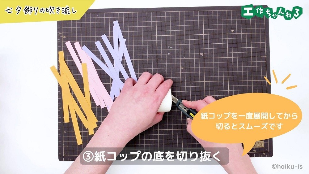 カッターで紙コップの底を切っている手元