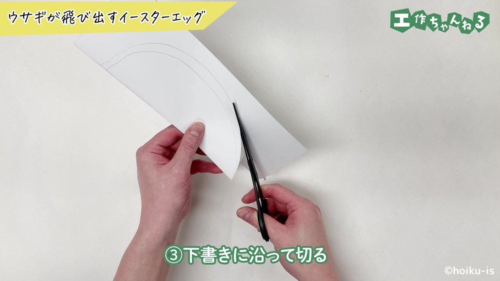 ハサミで白い画用紙を切っている手